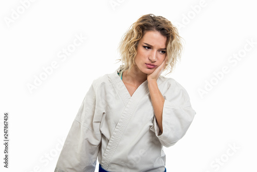 Portrait of female wearing martial arts uniform making tooth ache gesture
