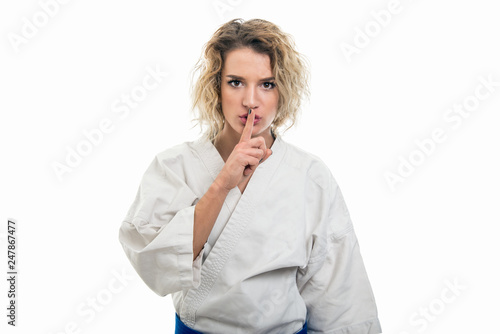 Portrait of female wearing martial arts uniform making silence gesture