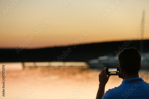 Man photographing sunset at the dock