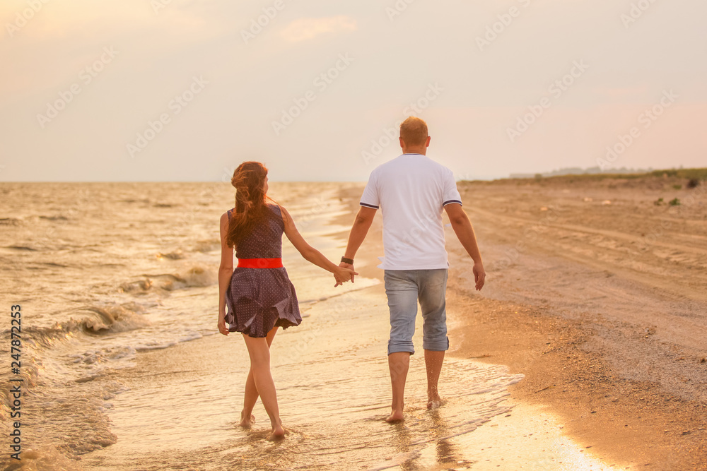 couple in love walks along the sea surf at sunset, romantic honeymoon, summer