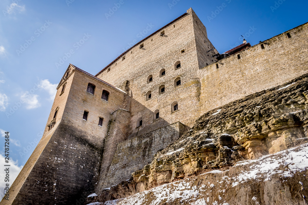 Narva castle on a snow covered cliff. Fortress built on rocks on a sunny, snowy day. 