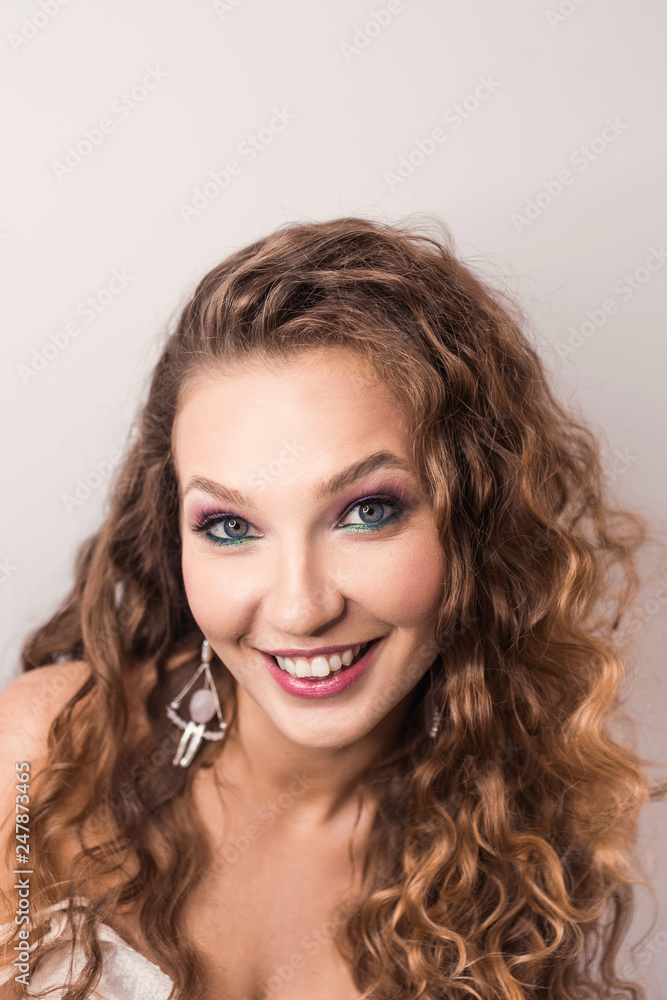 portrait beautiful young blonde curly girl posing in the studio with professional make-up and open tooth smile pink mood portrait beautiful young blonde curly girl posing in the studio with professional make-up and open tooth smile pink mood