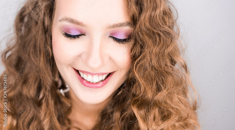 portrait beautiful young blonde curly girl posing in the studio with professional make-up and open tooth smile pink mood portrait beautiful young blonde curly girl posing in the studio with professional make-up and open tooth smile pink mood