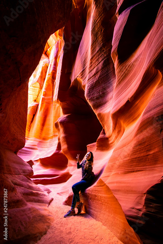 Happy young woman making peace and love sign with her hands inside of the Antelope Canyon, Arizona, USA. 