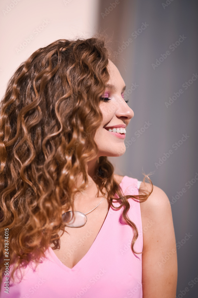close-up portrait of a young beautiful sexy girl with curly hair in a pink feather dress  smiling lifestyle on a street in sunny day