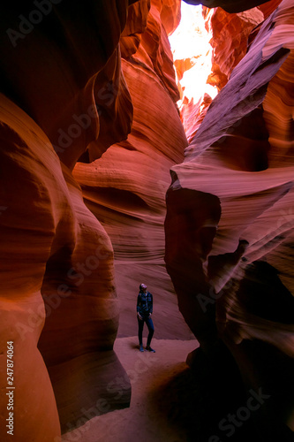 Impressed young traveler woman looking up inside of the Antelope Canyon, Arizona, USA. 