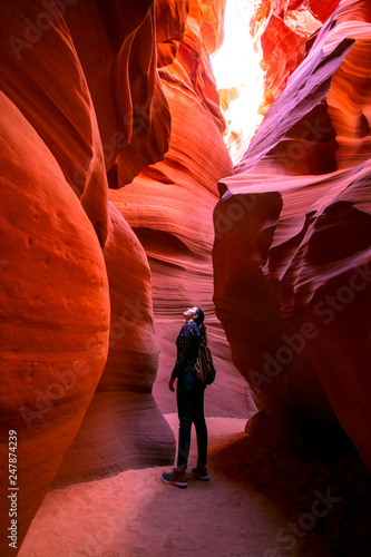Impressed young traveler woman looking up inside of the Antelope Canyon, Arizona, USA. 