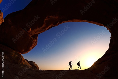 Couple hiking at Rock-Arch Al Kharza, Wadi Rum, Jordan, Asia photo