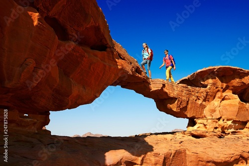 Couple hiking at Rock Arch, Al Borg Alsagheer, Wadi Rum, Jordan, Asia photo
