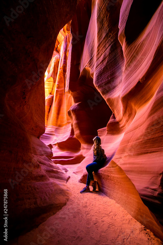 Impressed young traveler woman looking up inside of the Antelope Canyon, Arizona, USA. 