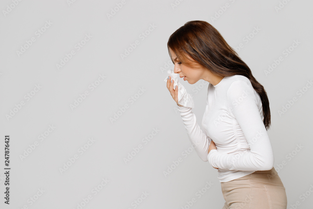 Studio portrait of cute unhealthy Caucasian female with paper napkin sneezing, experiences allergy symptoms, caught a cold.Sick desperate woman has flu.Rhinitis, cold, sickness, allergy concept Studio portrait of cute unhealthy Caucasian female with paper napkin sneezing, experiences allergy symptoms, caught a cold.Sick desperate woman has flu.Rhinitis, cold, sickness, allergy concept
