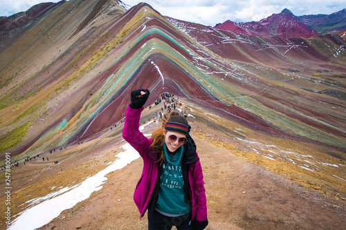 Young woman celebrating with the fist held high, after a long trekking through Vinicunca (rainbow mountain) Perú.
