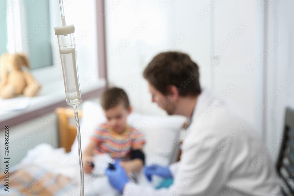Doctor examining little child in hospital, focus drip chamber Doctor examining little child in hospital, focus drip chamber