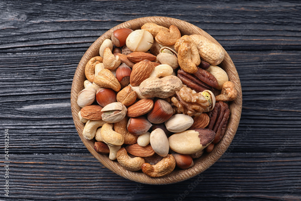 Bowl with organic mixed nuts on wooden background, top view Bowl with organic mixed nuts on wooden background, top view
