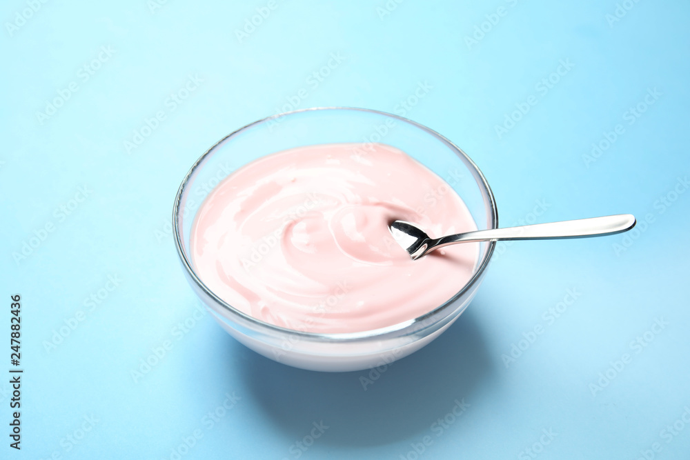 Glass bowl with creamy yogurt and spoon on color background Glass bowl with creamy yogurt and spoon on color background