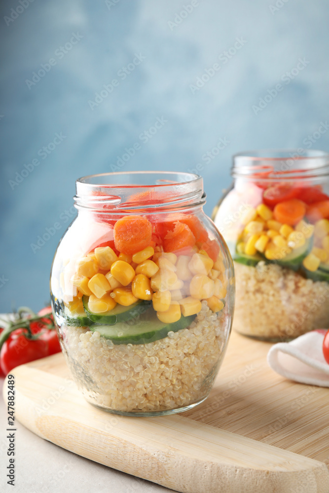 Jars with healthy quinoa salad and vegetables on table. Space for text Jars with healthy quinoa salad and vegetables on table. Space for text