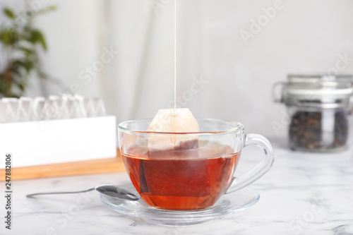 Brewing tea with bag in cup on table