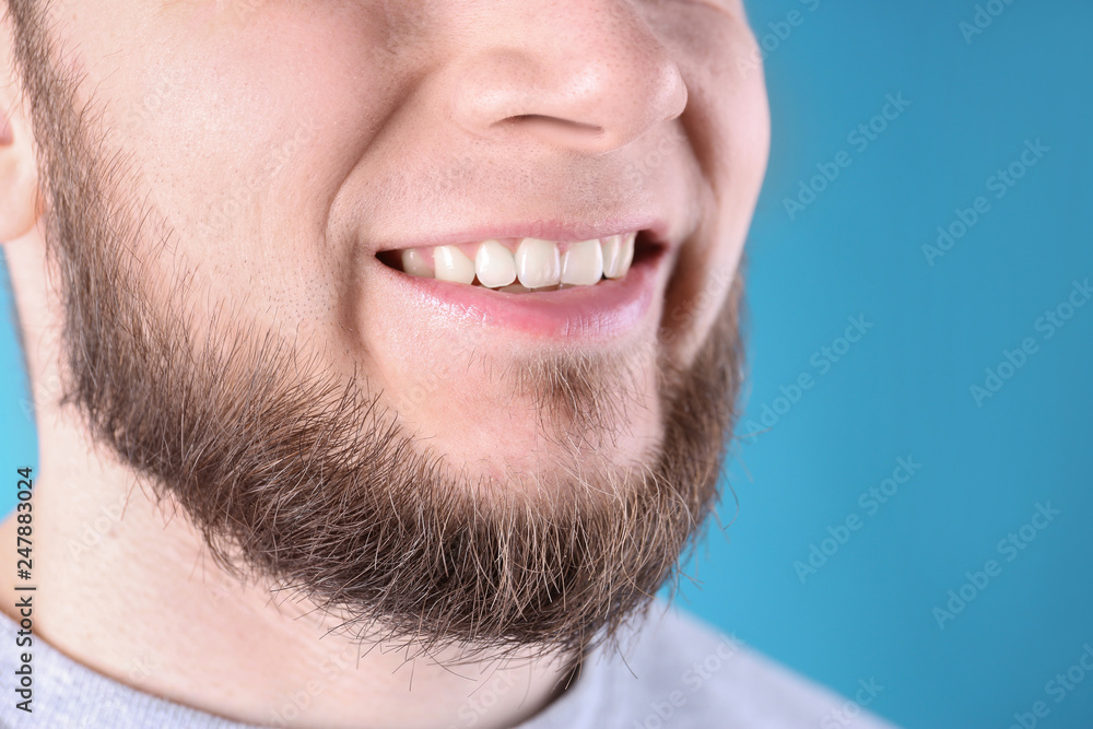 Obraz premium Young man with healthy teeth and beautiful smile on color background, closeup