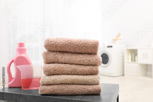 Stack of clean towels and liquid detergent on table in bathroom. Space for text