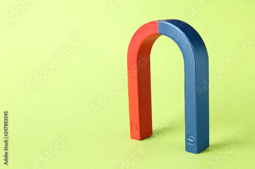 Red and blue horseshoe magnet on color background. Space for text