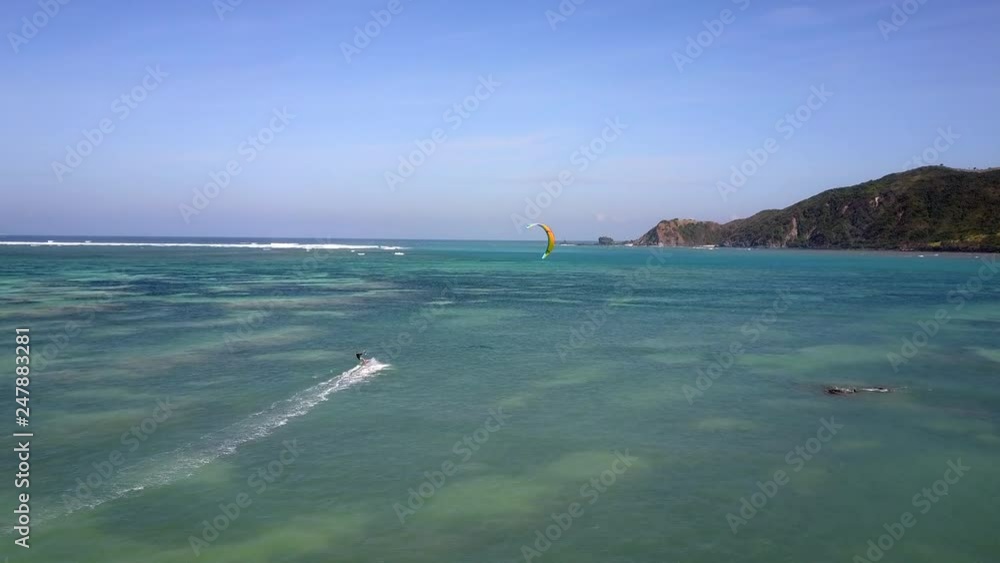Beautiful aerial shot of a solo kiteboarder kitesurfing in the bay with