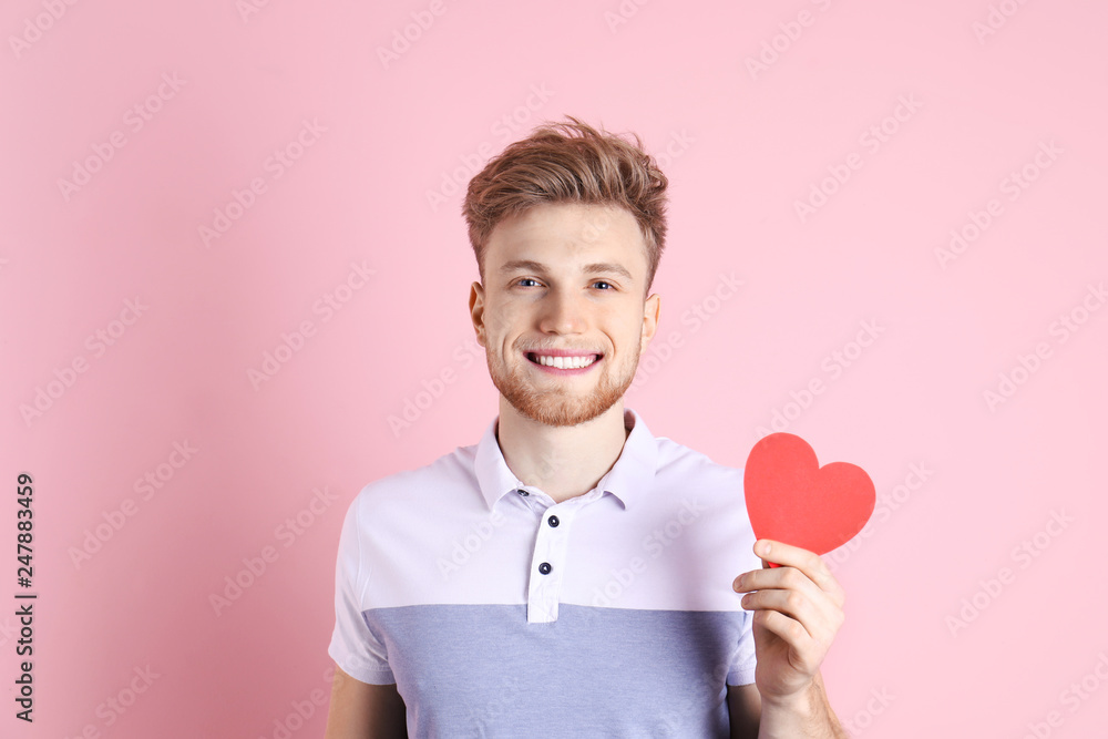 Portrait of young man with paper heart on color background Portrait of young man with paper heart on color background