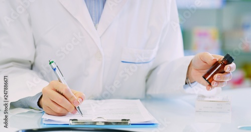 Cuadro en lienzo Hand close up of a  young woman pharmacist consultant checking medicines list on tablet in a drug store
