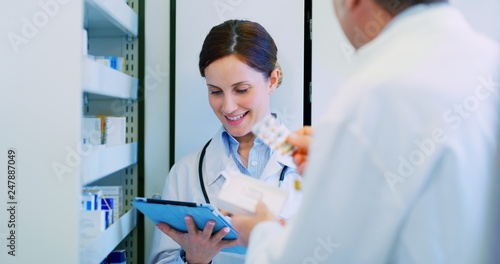 Quadro em tela Portrait of young woman pharmacist handing over prescribed medicines to her colleague in drugs store