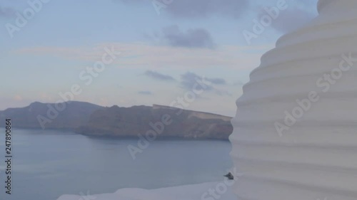 Tracking back from a majestic view of the Aegean sea engulfed by dark Santorini clifs, to reveal a large white pottery decoration vase. Location Oia, Santorini. photo