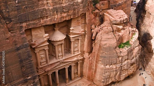 Aerial view of the beautiful Al Khazneh (The Treasury) with tourists admiring it from below. Petra is a historical and archaeological city in southern Jordan.