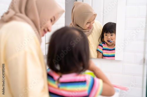 asian muslim mom brush her kid s teeth in the bathroom