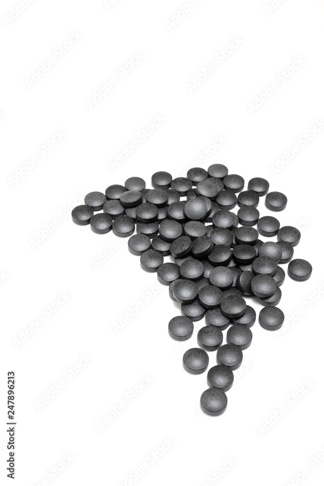Round black pills of iron on a white background. SUPPLEMENT Round black pills of iron on a white background. SUPPLEMENT