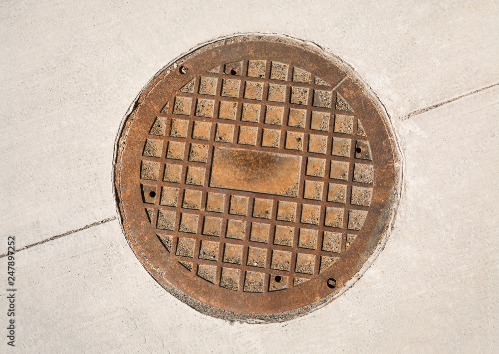 Cast iron manhole hatch on concrete pavement