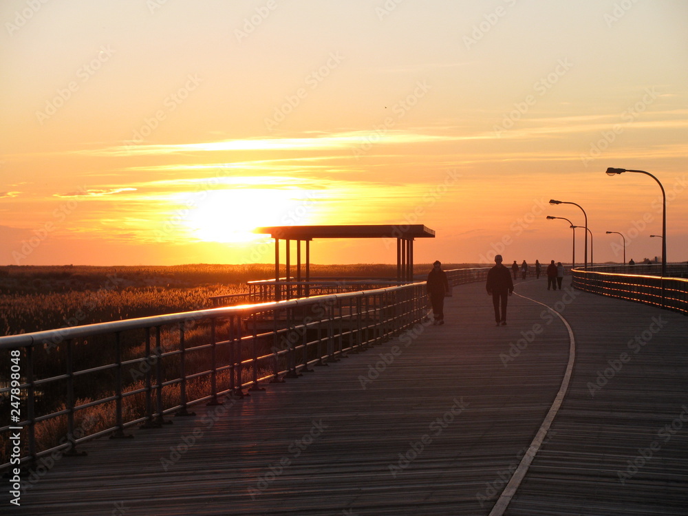 An orange and yellow sunset at Jones Beach boardwalk in Long Island, New York.