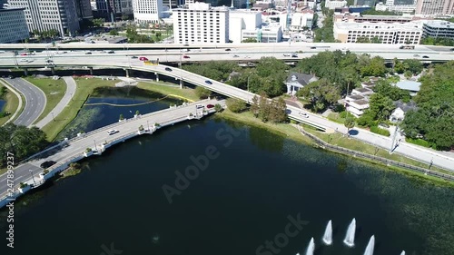 Drone clip tilts up to reveal Downtown Orlando over small pond. photo