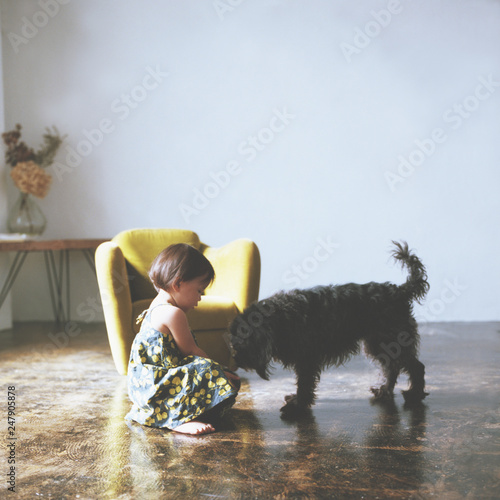 Side view of girl with dog sitting on floor at home