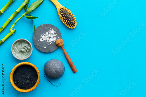 Hair care, hair spa. Cosmetics based on bamboo charcoal powder near comb on blue background top view copy space
