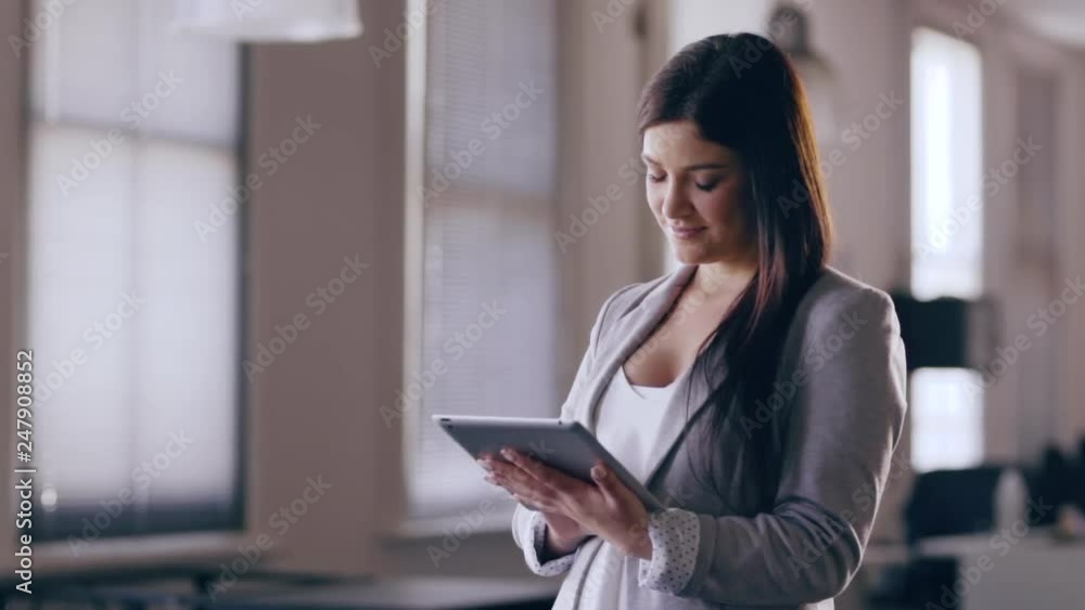 Young professional business woman working on a tablet in an office smiling Young professional business woman working on a tablet in an office smiling