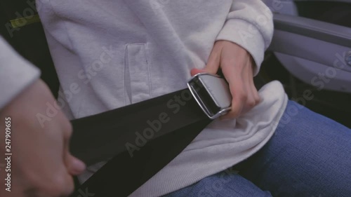 Woman's hands fasten safety seat belt on the plane. Hands close-up. Side view.