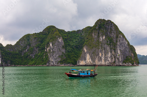 Halong bay rock formations with a Vietnamese traditional blue fishing boat, UNESCO world natural heritage, Vietnam. © Ovnigraphic