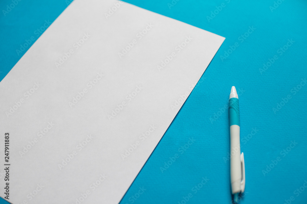 White paper list and pen on blue background White paper list and pen on blue background