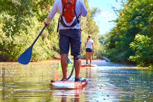 Close-up of a woman and man legs on stand up paddle in water photo
