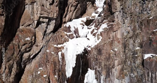 Wallpaper Mural Waterfall among rocks. Winter waterfall in the mountains. Lies snow, are rising ate and wood. Ice on the edges of the cliff and waterfall. Shooting at a drone. Sometimes you can see a group of people. Torontodigital.ca