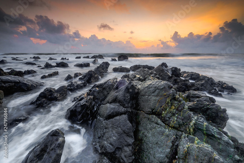 A scenery of sunrise with amazing unique rock formation and beautiful flow of wave at Kemasik beach, Terangganu Malaysia. Soft focus during long exposure shot.