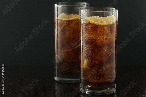 Glasses with cuba libre cocktail or cola with ice or cold tea with lemon