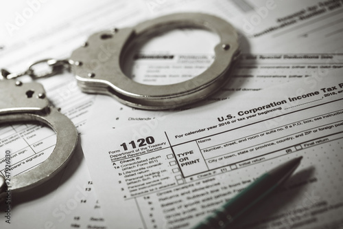 tax evasion concept - tax form 1120 and handcuffs photo