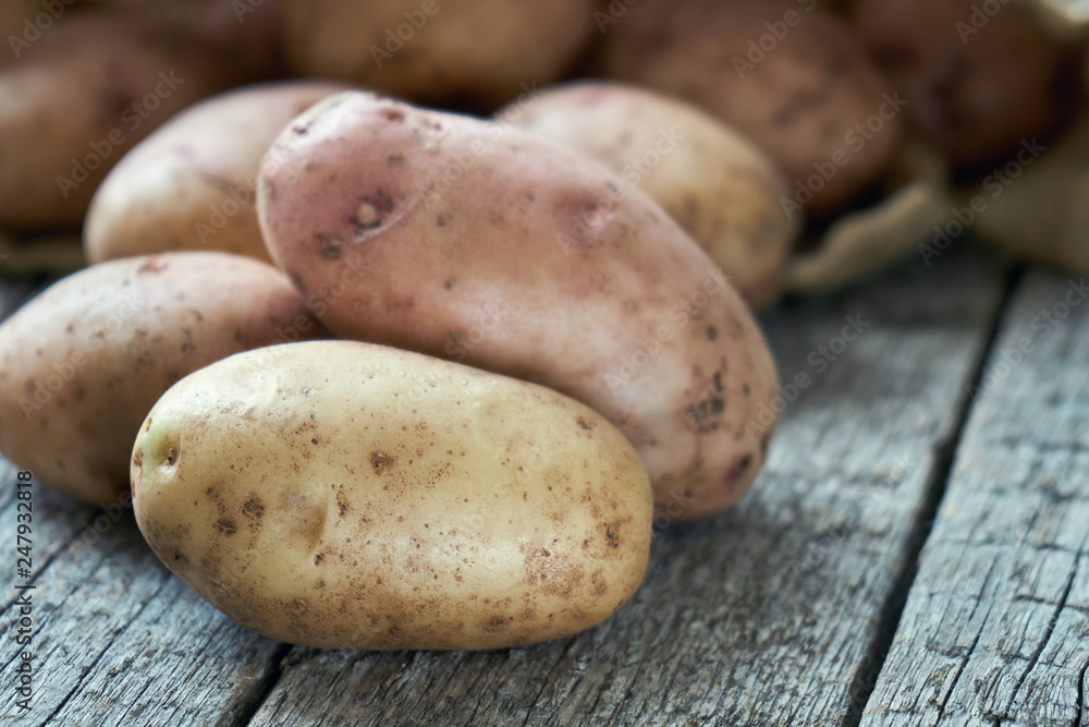Potato tubers lying on the rough wooden boards Potato tubers lying on the rough wooden boards