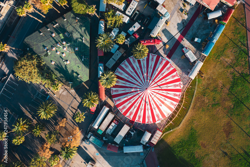 Aerial; drone view of bright round dome of street circus chapiteau; warm morning light on the roof of travelling circus; attractions for tourists and locals; used for theater and entertainment events