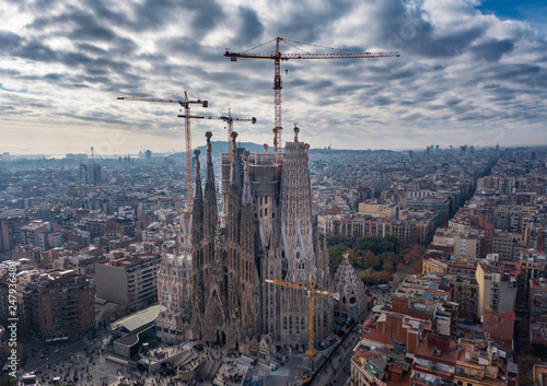 Aerial; drone view of main Gaudi project Sagrada Familia Temple; majestic building towering over the rooftops of Eixample district; long construction of the temple "business card" of Barcelona, Spain
