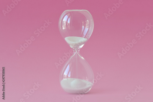 Hourglass on pink background - Concept of health, fertility and biological clock in women